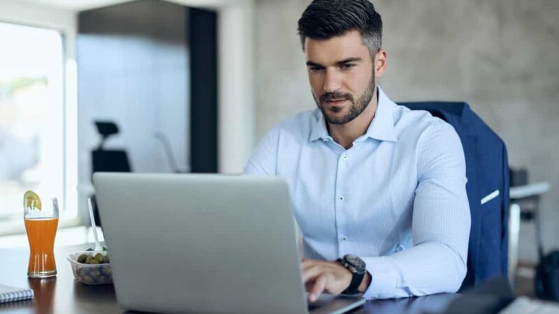 male-entrepreneur-using-computer-while-working-office-min